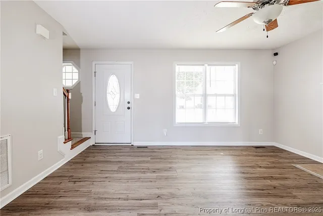 an empty room with wooden floor and windows