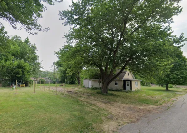 a front view of a house with a yard and trees