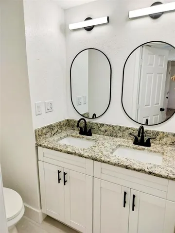 a bathroom with a granite countertop toilet sink and mirror