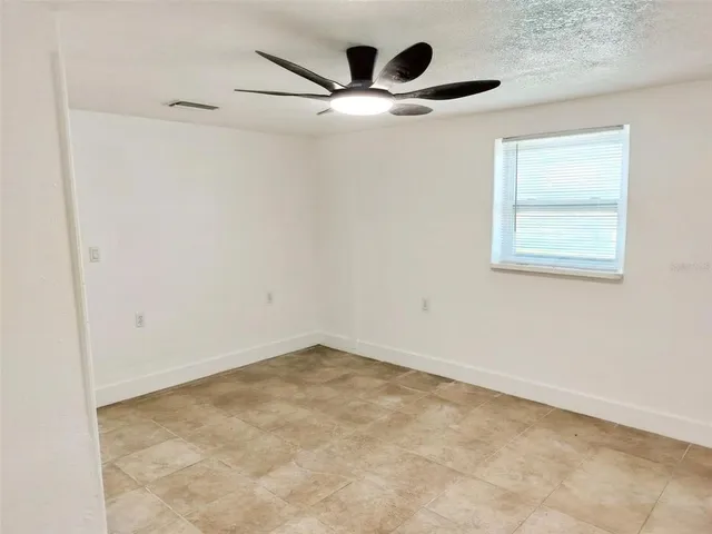 an empty room with windows and ceiling fan