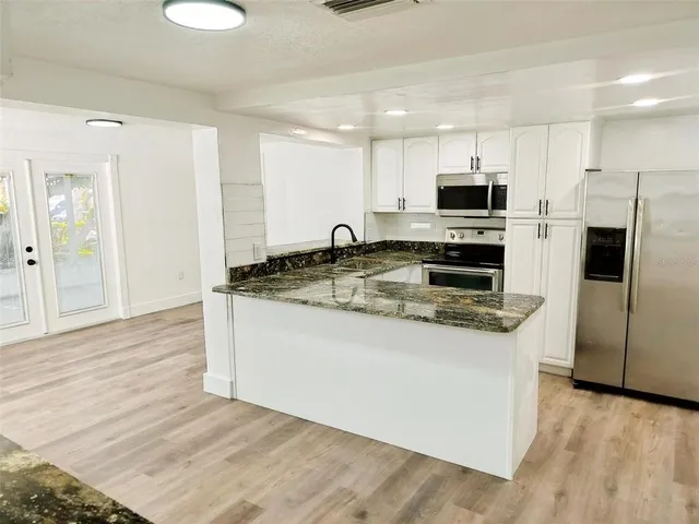 a kitchen with stainless steel appliances granite countertop a stove a sink and a refrigerator
