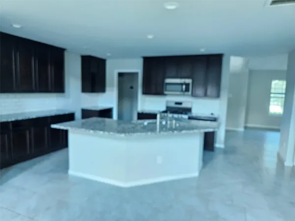 a view of living room with stainless steel appliances kitchen island granite countertop furniture and wooden cabinets