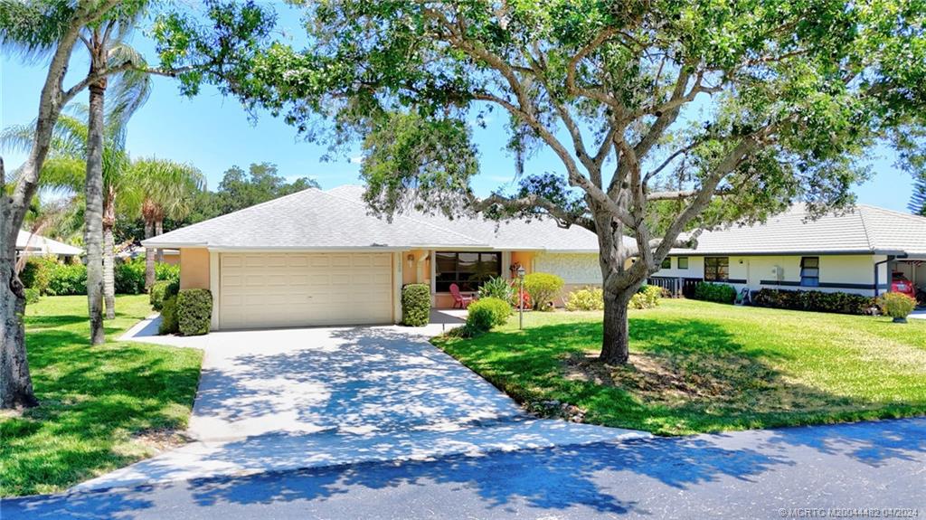 5139 Southeast Hanson Circle Stuart, FL 34997 - Photo 1 of 27 a front view of a house with a garden and trees