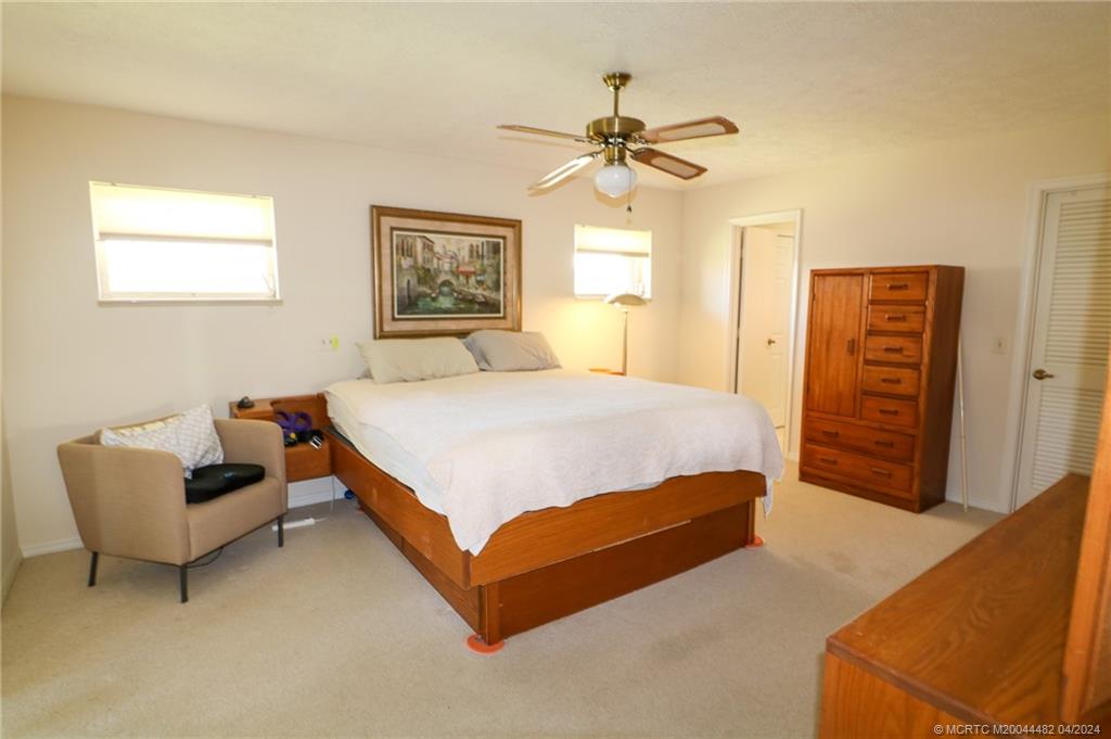 5139 Southeast Hanson Circle Stuart, FL 34997 - Photo 17 of 27 a bedroom with a bed and a chandelier