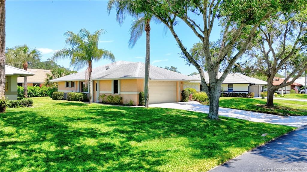 5139 Southeast Hanson Circle Stuart, FL 34997 - Photo 2 of 27 a front view of a house with a yard and palm trees