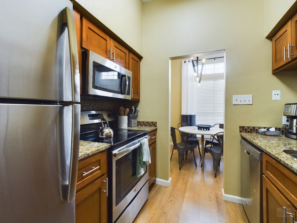 2811 Rio Grande Street, Unit 204 Austin, TX 78705 - Photo 9 of 31 a kitchen with stainless steel appliances granite countertop a stove top oven a sink a dining table and chairs with wooden floor