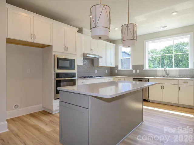 a kitchen with stainless steel appliances granite countertop a sink a stove a refrigerator and island with wooden floor