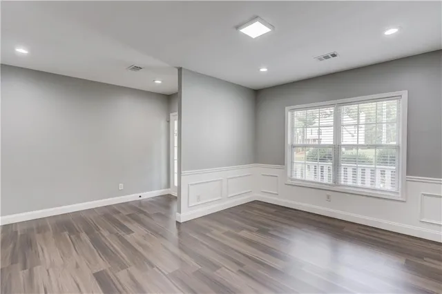 an empty room with wooden floor and windows