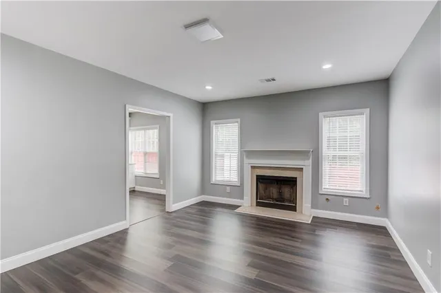 an empty room with wooden floor fireplace and windows