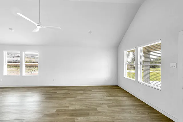 a view of an empty room with a window and wooden floor
