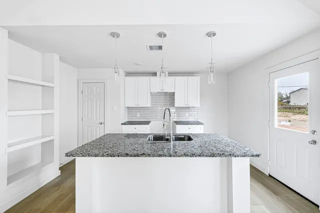 a kitchen with kitchen island granite countertop a table and cabinets