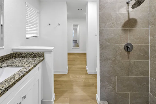 a bathroom with a granite countertop sink a toilet and shower