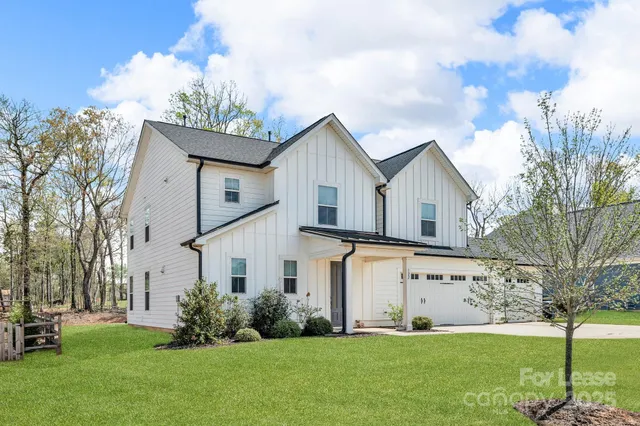 a front view of a house with a yard and trees