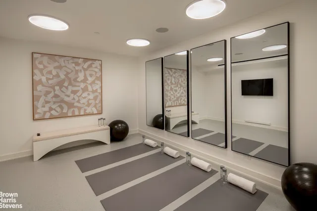 a room with gym equipment and a glass door shower