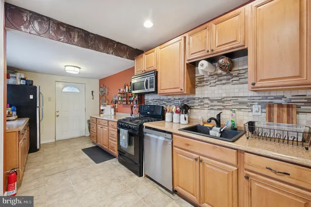 a kitchen with stainless steel appliances granite countertop a sink a stove cabinets and a refrigerator