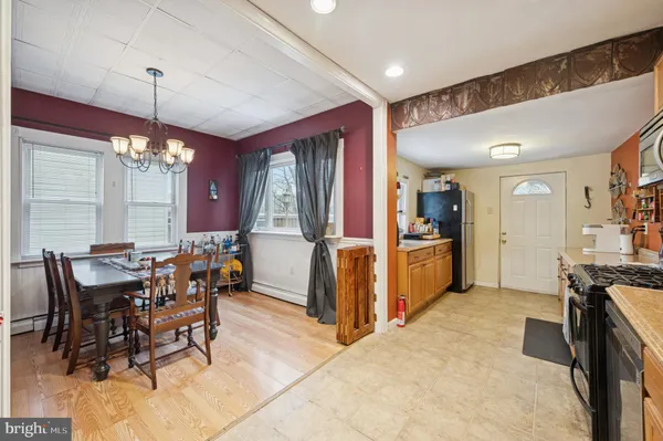 a kitchen with stainless steel appliances kitchen island granite countertop a dining table chairs and a refrigerator
