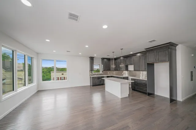 a open kitchen with stainless steel appliances granite countertop a refrigerator a sink dishwasher a oven and a large window with wooden floor