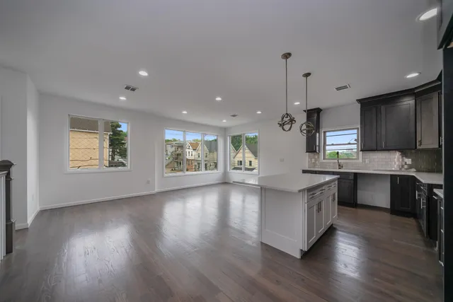 a large kitchen with stainless steel appliances granite countertop a stove a sink dishwasher a refrigerator and a wooden floor