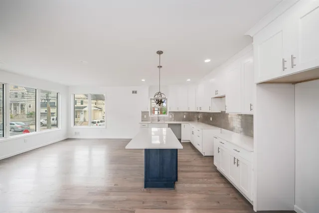 a large white kitchen with wooden floors and view