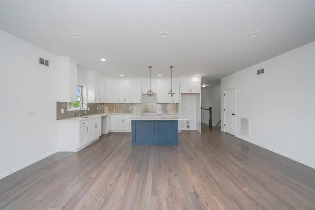 a large kitchen with stainless steel appliances granite countertop a large counter top and a stove with wooden floors