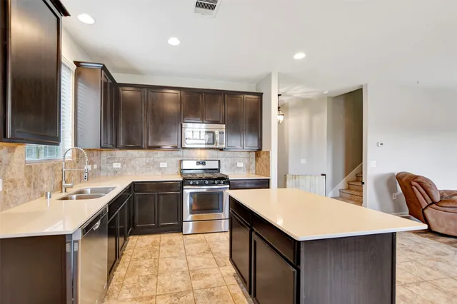 a large kitchen with a stove a sink dishwasher a refrigerator and a oven with wooden floor