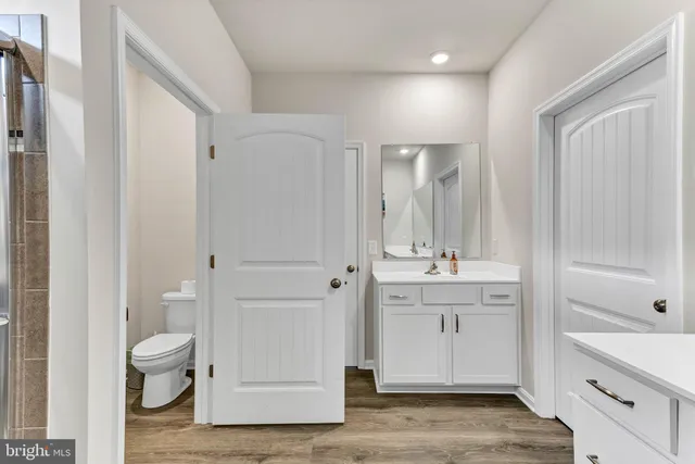 a bathroom with a granite countertop toilet a sink and a mirror