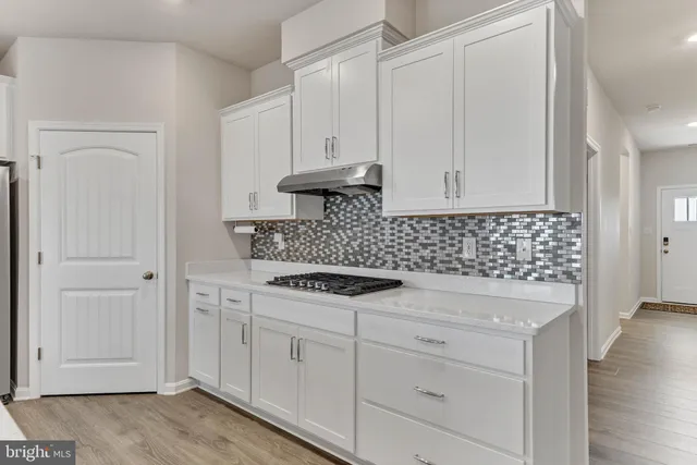 a kitchen with white cabinets and sink
