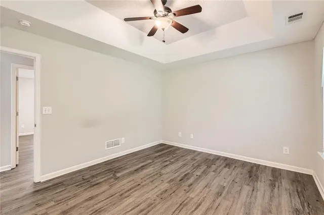 an empty room with wooden floor fan and windows