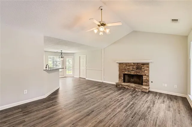 an empty room with wooden floor fireplace and windows