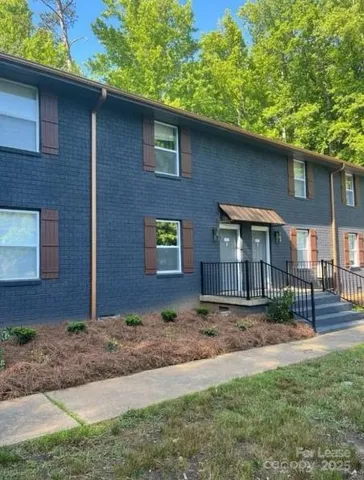 a brick house next to a yard with large trees