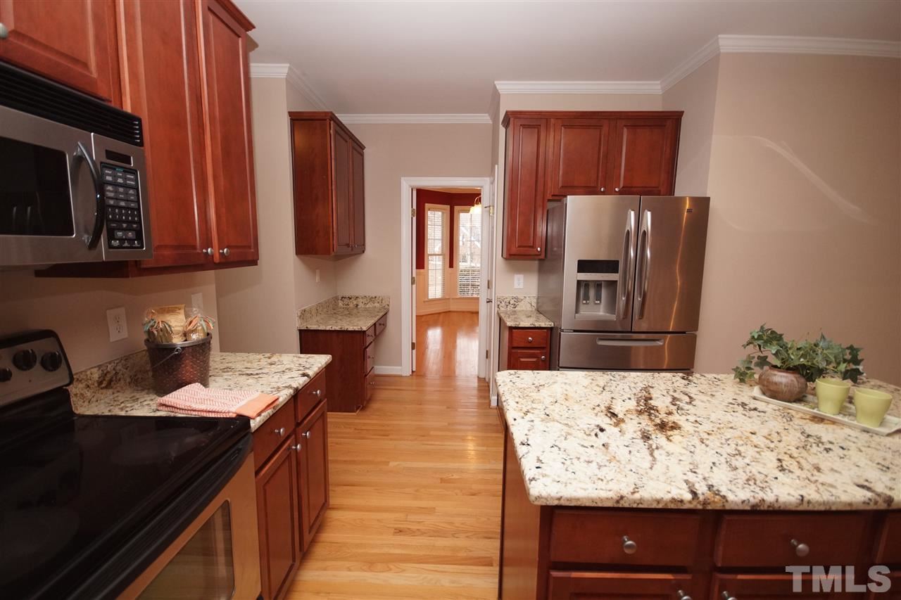 12736 Amoretto Way Raleigh, NC 27613 - Photo 10 of 25 a kitchen with kitchen island granite countertop wooden cabinets a stove top oven a sink and dishwasher