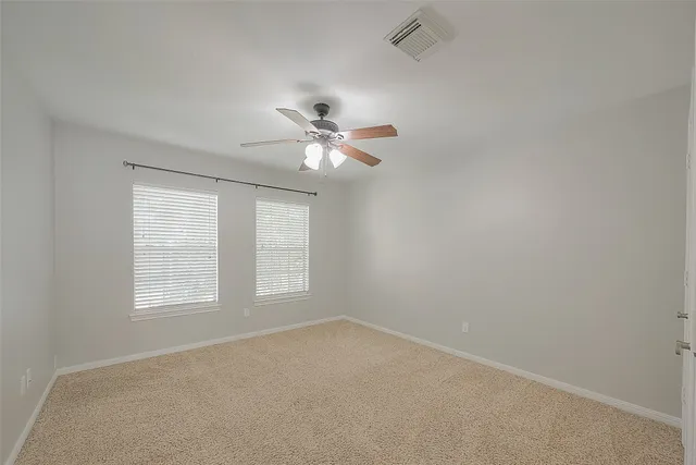an empty room with windows and fan