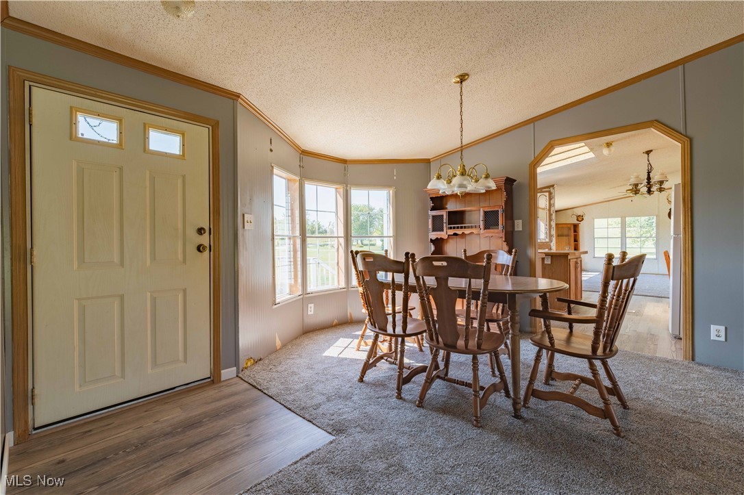 73550 Old Twenty One Road Kimbolton, OH 43749 - Photo 10 of 35 Dining space featuring a textured ceiling, lofted ceiling, hardwood / wood-style flooring, ornamental molding, and a chandelier