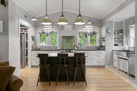 a kitchen with stainless steel appliances granite countertop a stove a refrigerator a sink dishwasher a dining table and chairs with wooden floor