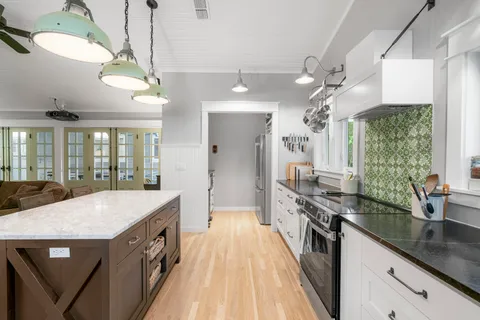 a large kitchen with kitchen island a large counter space a sink appliances and a large window