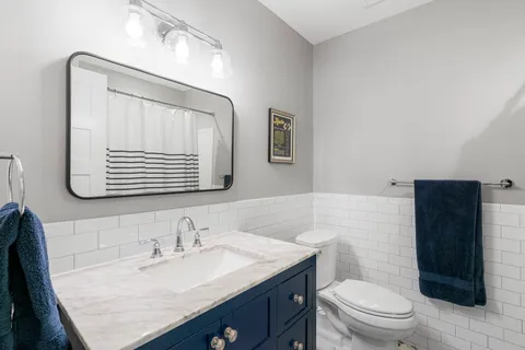 a bathroom with a granite countertop sink toilet a mirror and shower