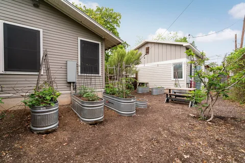 a view of a backyard with table and chairs potted plants