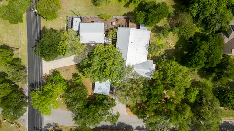 an aerial view of residential house with outdoor space and trees all around