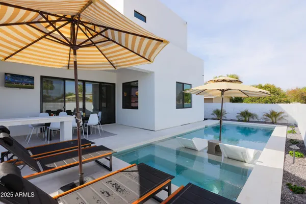 a patio with a table and chairs and potted plants