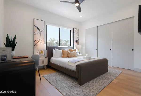 a bedroom with a bed a couch and a flat tv screen