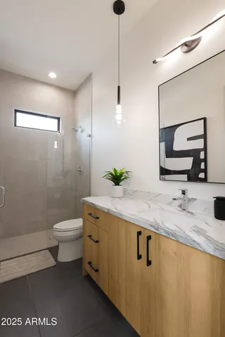 a bathroom with a granite countertop sink a toilet and a mirror