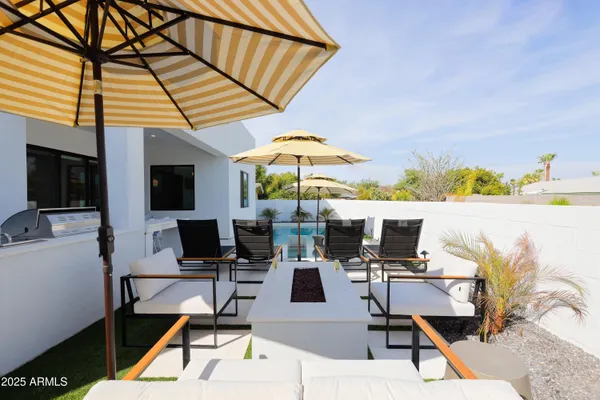 a patio with a table and chairs under an umbrella