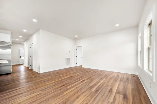 a view of empty room with wooden floor and windows