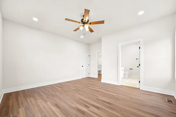an empty room with wooden floor ceiling fan and windows