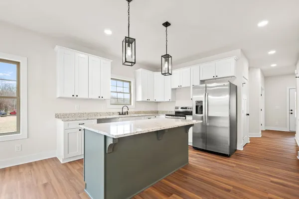 a kitchen with stainless steel appliances granite countertop a sink a stove a refrigerator and island with wooden floor