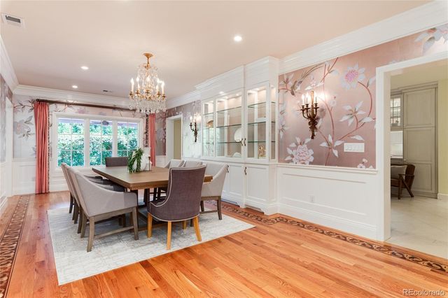 a spacious bedroom with a bed a chandelier and potted plant on the dresser