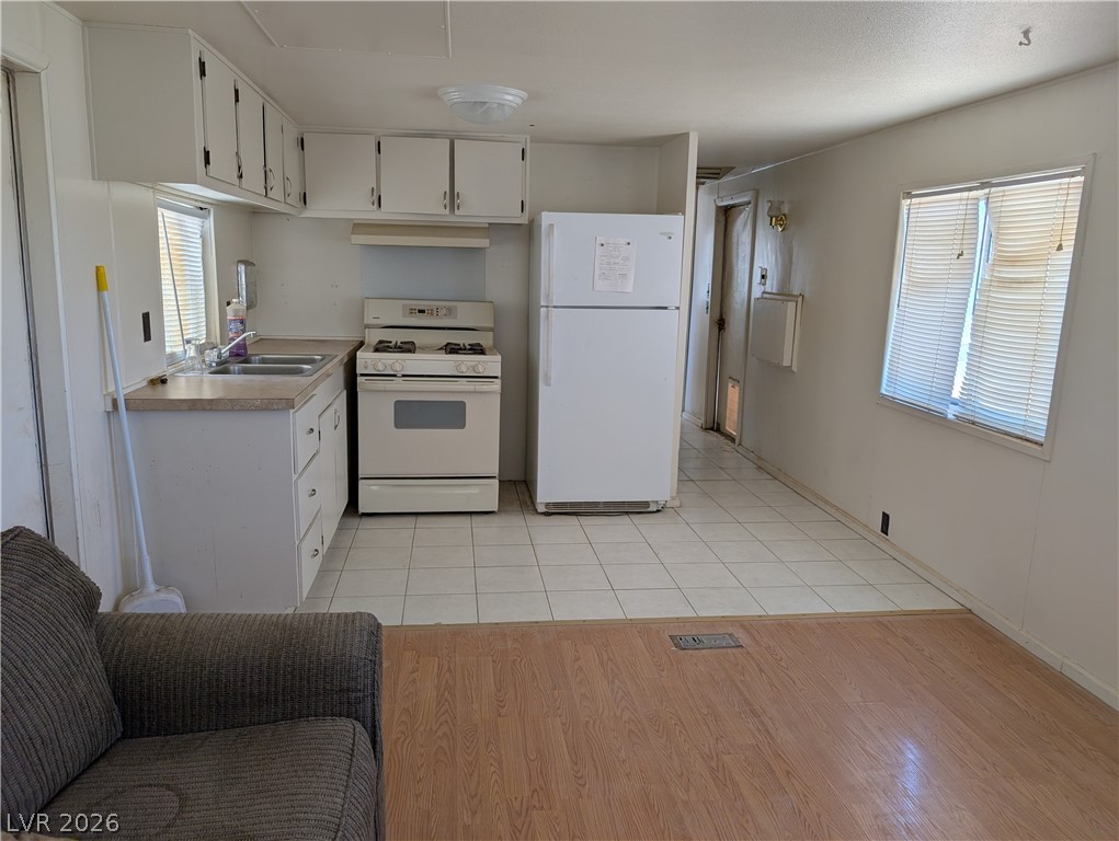 2350 Shawnee Street Sandy Valley, NV 89019 - Photo 5 of 38 Kitchen featuring white appliances, white cabinetry, light countertops, and a sink