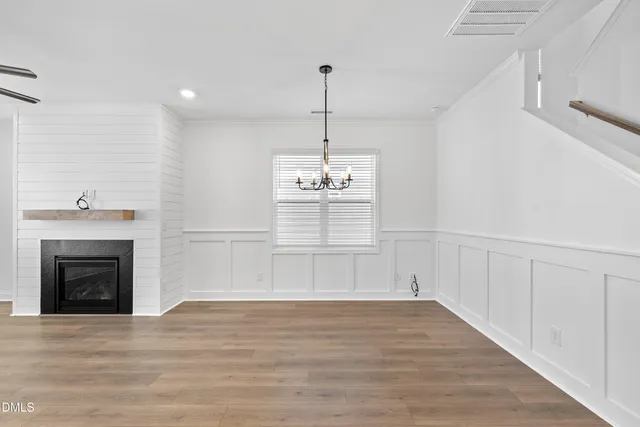 a view of an empty room with wooden floor fireplace and a window