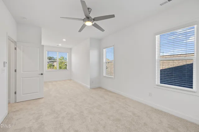 an empty room with windows and fan