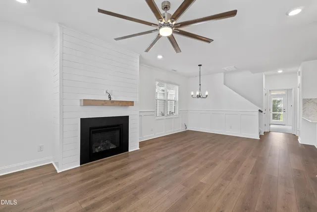 a view of an empty room with wooden floor fireplace and a window